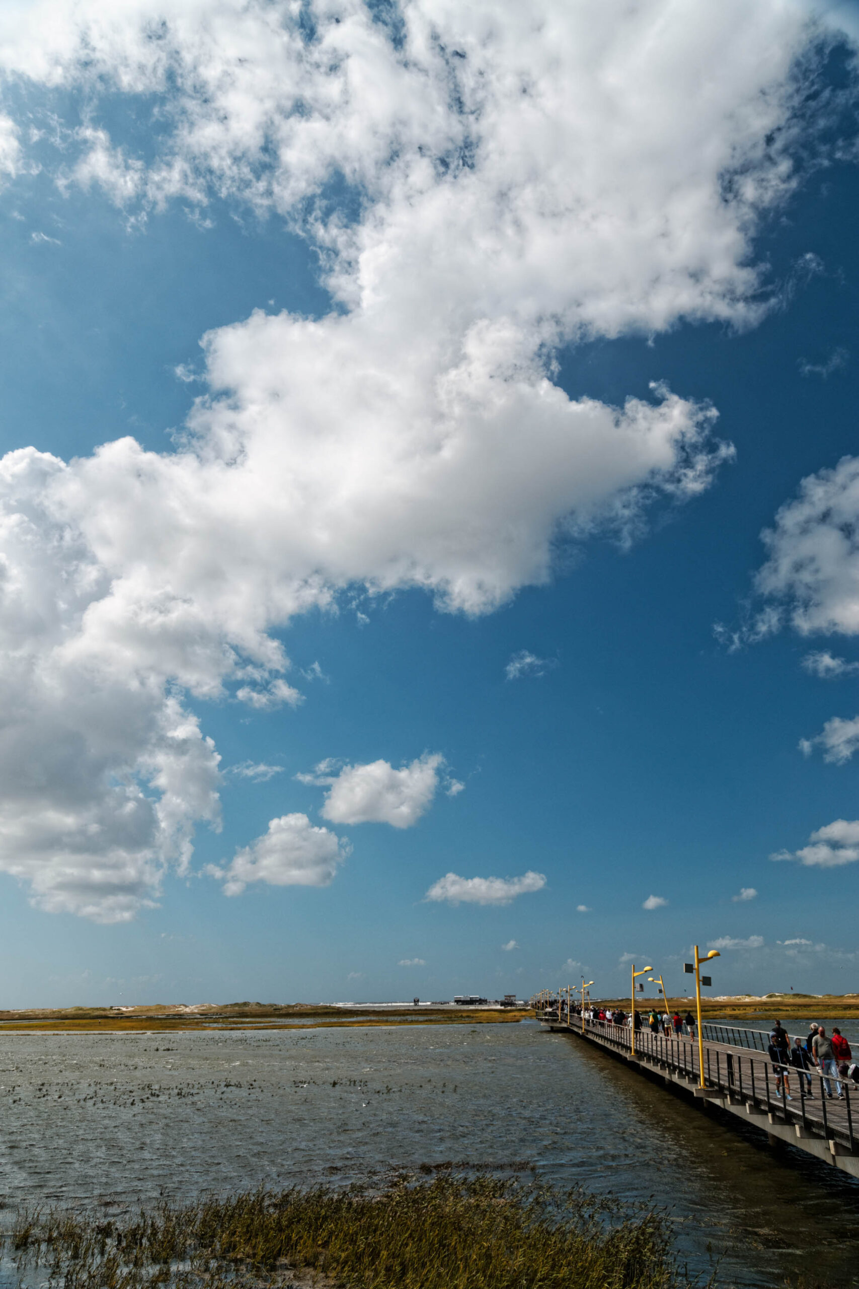 Die Aufnahme zeigt eine typische Landschaft von St. Peter-Ording an der Nordsee. Ein langer, breiter Steg, der sogenannte