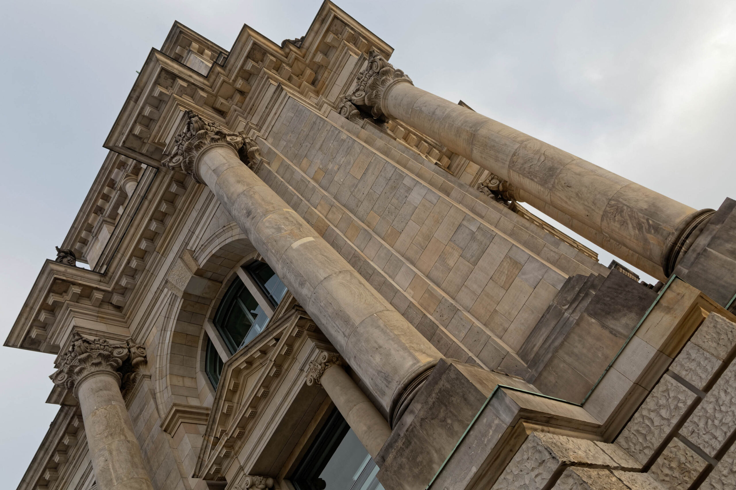 Die Aufnahme zeigt eine ungewöhnliche Perspektive auf das Berliner Schloss. Die Säulen dominieren das Bild und scheinen sich in den Himmel zu erheben. Das Portal ist reich verziert und zeigt Details der Architektur des Schlosses. Die Aufnahme wurde im März 2019 aufgenommen und fängt die Schönheit und den historischen Wert des Schlosses ein.
