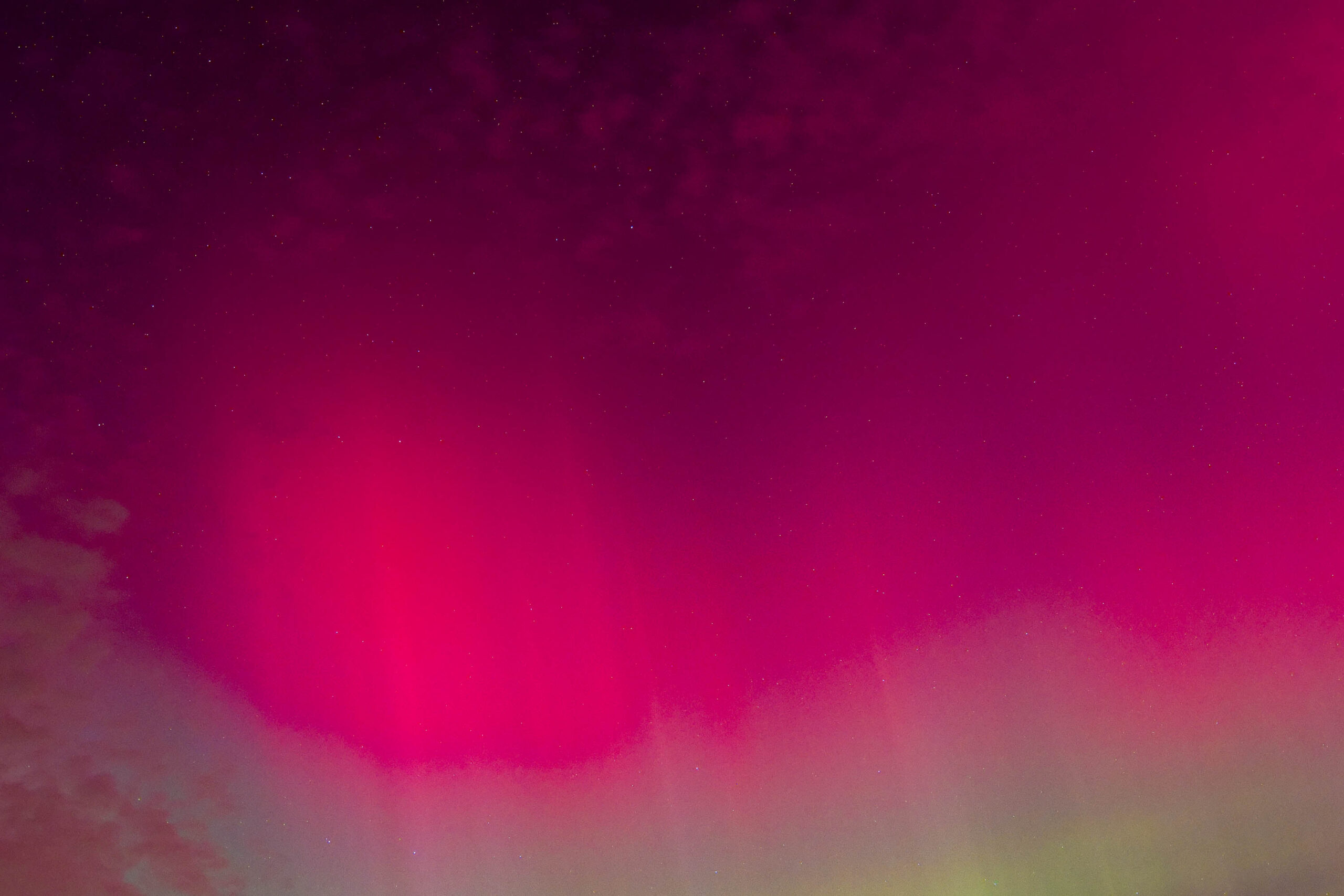 Das Foto zeigt ein beeindruckendes Polarlicht, das den Nachthimmel in leuchtenden Farben erhellt. Die Farbpalette reicht von einem intensiven Pink bis zu einem sanften Grün, was eine faszinierende visuelle Darstellung erzeugt. Der Himmel ist klar und sternenklar, was die Schönheit des Polarlichts noch verstärkt. Der Horizont ist kaum erkennbar, was den Eindruck eines unendlichen, himmlischen Schauspielers vermittelt. Die Aufnahme fängt die Magie und das Mysterium des Polarlichts ein und erzeugt eine Atmosphäre der Ehrfurcht und des Staunens.